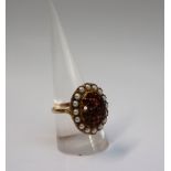 A 9ct yellow gold dress ring, set with round faceted garnets, surrounded by pearls, size S,