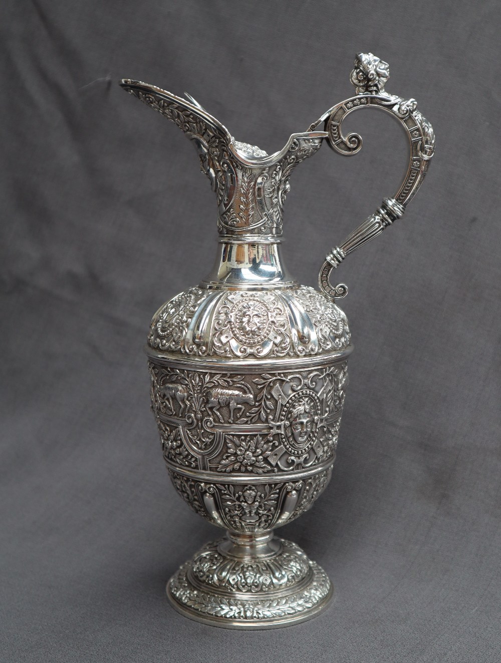 A Victorian silver claret jug, after Cellini, all over decoration of masks and rams,