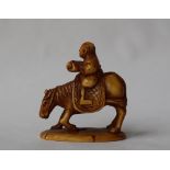 A 19th century Japanese ivory netsuke depicting a man riding a horse reading, on an oval base,