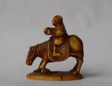A 19th century Japanese ivory netsuke depicting a man riding a horse reading, on an oval base,