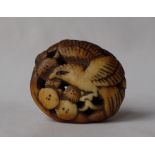 A Japanese carved stag antler manju netsuke in the form of an eagle amongst flower heads,