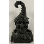 A cast iron door stop in the form of a gnome with a curling hat, 24.