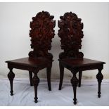 A pair of continental carved oak hall chairs, the back decorated with scrolling leaves and a shell,