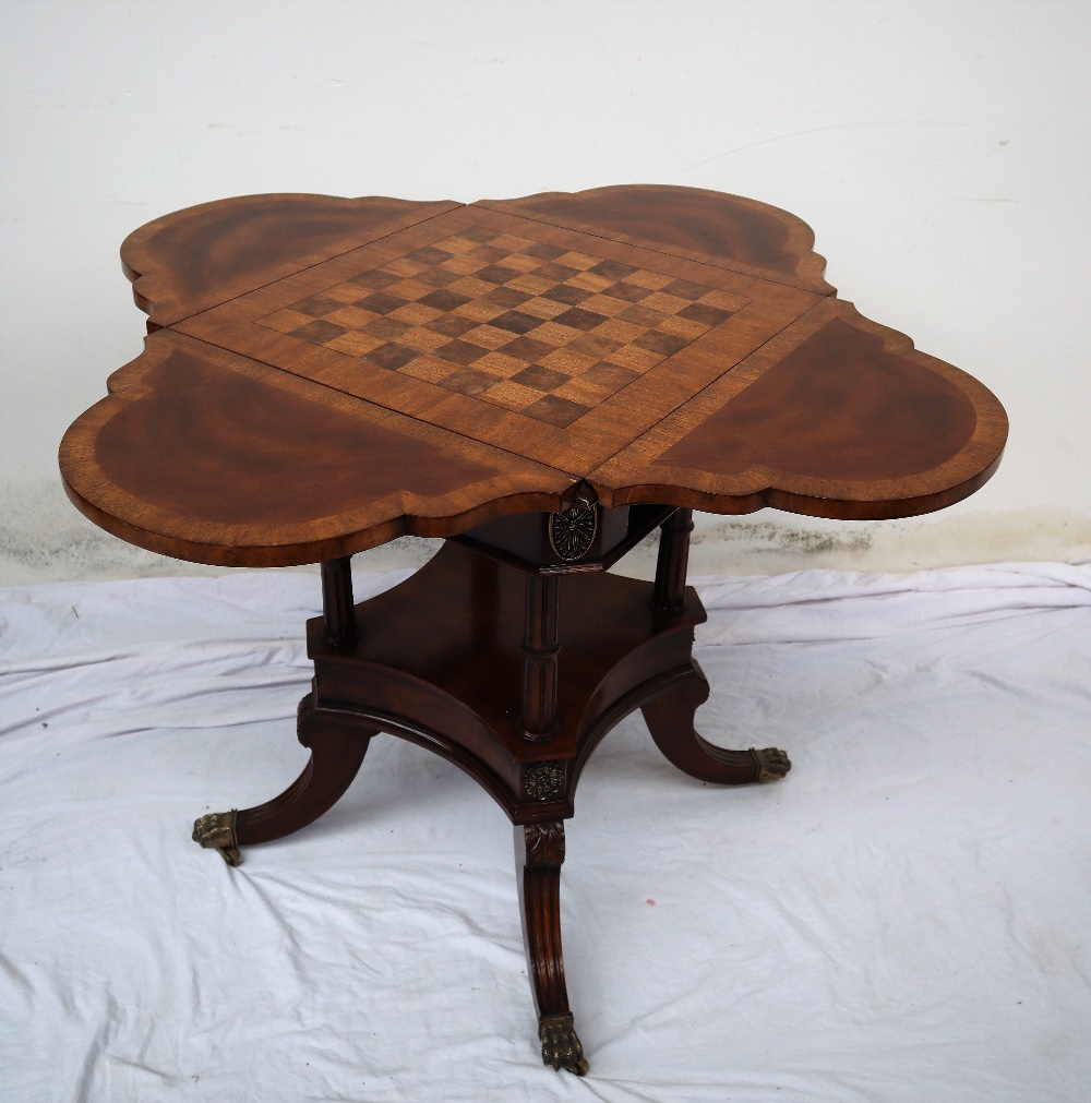 A reproduction mahogany games table, of lobed shape with four drop flaps,