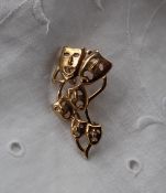 A 9ct yellow gold brooch depicting graduated theatrical masks, approximately 5.