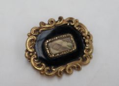 A Victorian mourning brooch, of rectangular shape with a scrolling border to a black ground,