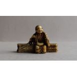 A 19th century Japanese ivory netsuke in the form of an elderly lady seated on a log,