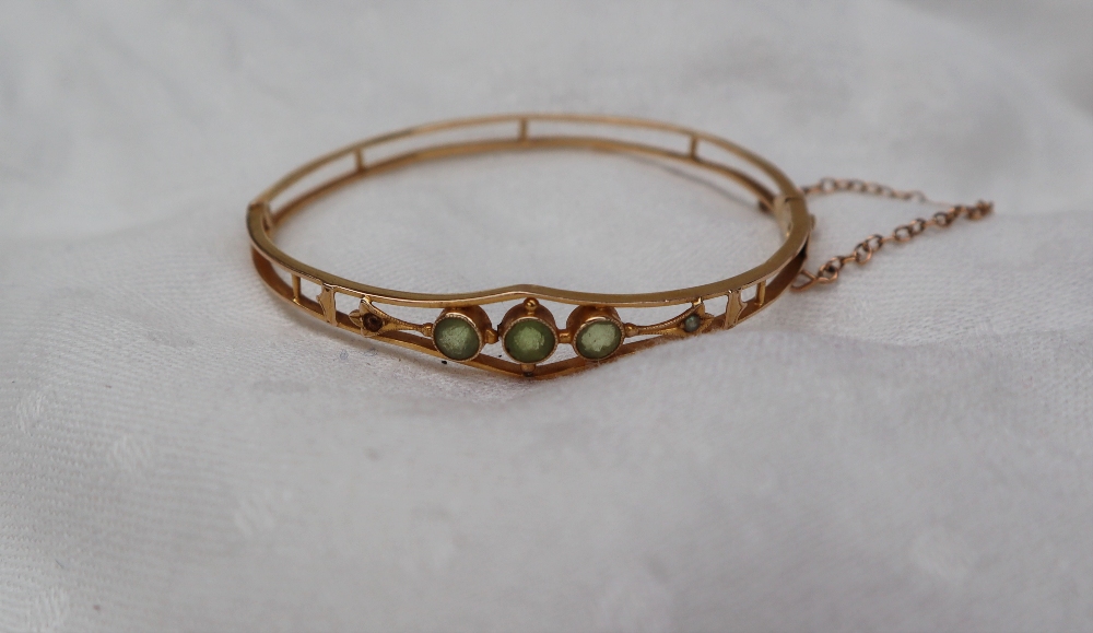 A 14ct yellow gold hinged bangle set with three round cut peridot and a seed pearl, - Image 2 of 3
