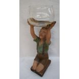A plaster figure of a boy kneeling with his arms raised holding a glass fish bowl,