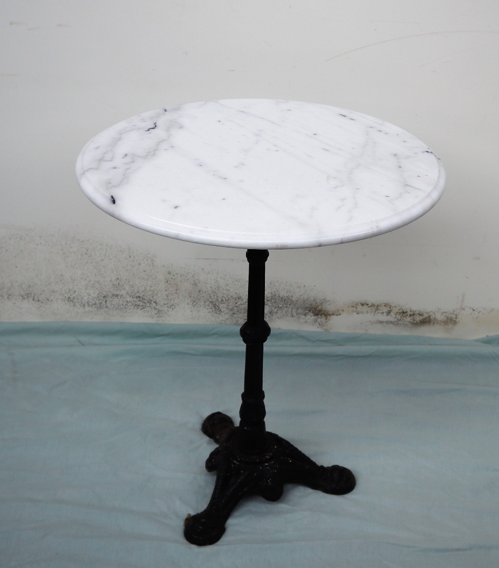 A garden table, the circular white marble top on a cast iron column and tripod base,