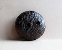 A 19th century Japanese carved wooden Manju netsuke of a stylised bird and feathers,