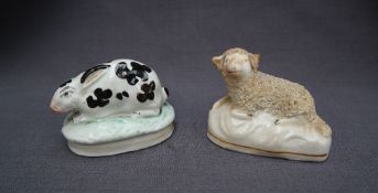 A 19th century Staffordshire pottery model of a crouching rabbit, on an oval base,