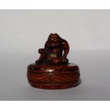 A 19th century Japanese carved wooden netsuke depicting an Oni seated upon a drum,