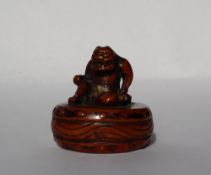 A 19th century Japanese carved wooden netsuke depicting an Oni seated upon a drum,