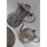 An Indian white metal coffee pot of panelled form embossed with animals and figures,