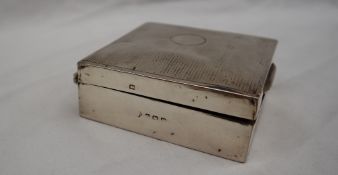 A silver cigarette box of square form with line decoration and a circular cartouche,