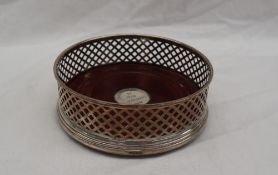 A modern silver wine coaster, with a lattice work edge and a turned mahogany base, 12.