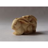 A 19th century Japanese ivory netsuke depicting mating hares, signed,