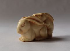 A 19th century Japanese ivory netsuke depicting mating hares, signed,