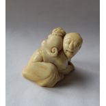 A 19th century Japanese ivory netsuke depicting a man on his hands and knees and a dog on his