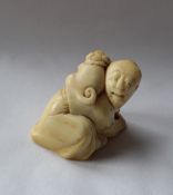 A 19th century Japanese ivory netsuke depicting a man on his hands and knees and a dog on his