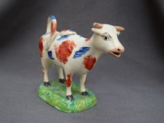 A 19th century pottery cow creamer with iron red and blue patches on a rectangular base,