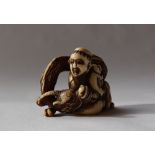 A 19th century Japanese ivory netsuke in the form of a seated figure holding a dog and a dragon