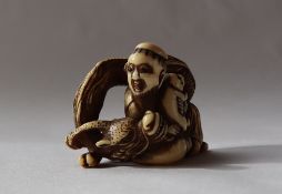 A 19th century Japanese ivory netsuke in the form of a seated figure holding a dog and a dragon