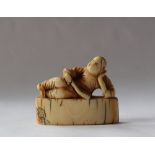 A 19th century Japanese ivory netsuke in the form of a man reclining with a fan in his hand on a