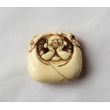 A 19th century Japanese ivory manju netsuke of a man with his head resting on his hands in a bag,