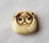 A 19th century Japanese ivory manju netsuke of a man with his head resting on his hands in a bag,