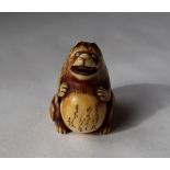 A 19th century Japanese ivory netsuke depicting a bear type figure with a distended stomach with
