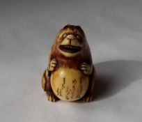 A 19th century Japanese ivory netsuke depicting a bear type figure with a distended stomach with