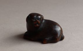 A 19th century Japanese carved wooden netsuke in the form of a recumbent dog, signed,