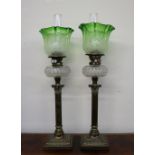 A matched pair of Victorian oil lamps with green to clear graded shades above a faceted clear glass