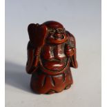 A Japanese carved wooden netsuke depicting Hotei holding a fan,