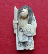 A 19th century Japanese ivory netsuke depicting a standing figure with rotating head holding a mask