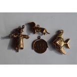 Four 9ct gold charms including a fish, scarecrow, dog and rotating Good Luck, approximately 7.