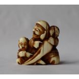 A 19th century Japanese ivory netsuke, in the form of a man and a boy holding a carrot,