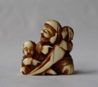 A 19th century Japanese ivory netsuke, in the form of a man and a boy holding a carrot,