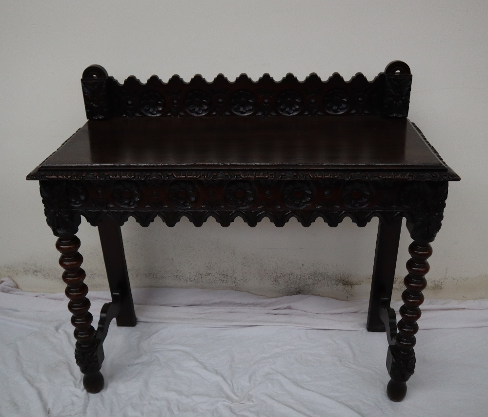 A 19th century carved oak side table, the raised back carved with arched and flowers heads,