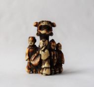 A 19th century Japanese ivory netsuke depicting four boys playing music around a pillar with a boy