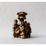 A 19th century Japanese ivory netsuke depicting four boys playing music around a pillar with a boy