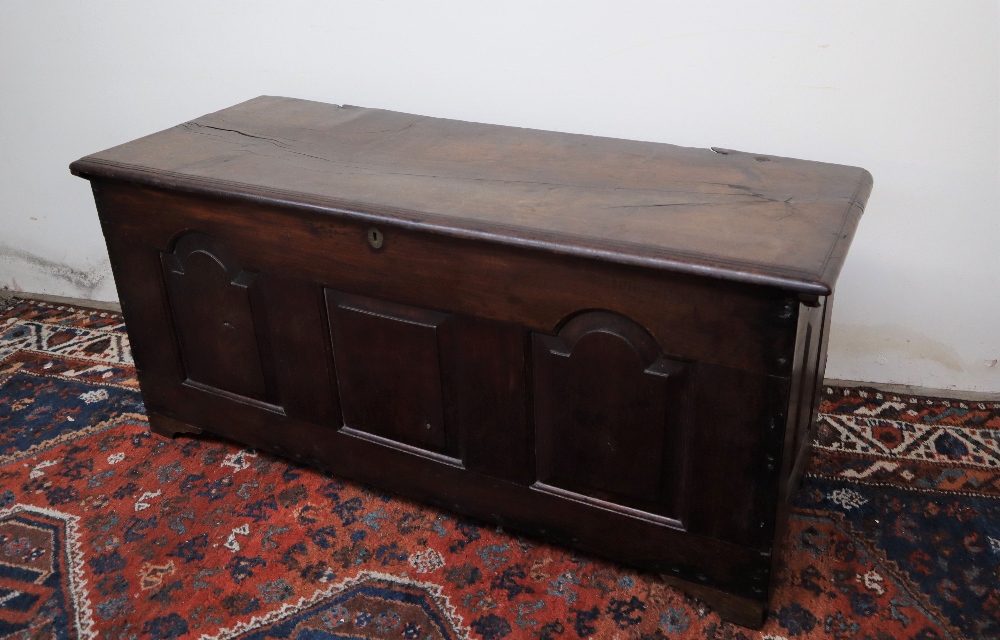 An 18th century oak coffer, the planked rectangular top above a three panelled front on stiles,