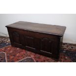 An 18th century oak coffer, the planked rectangular top above a three panelled front on stiles,