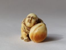 A 19th century Japanese ivory netsuke in the form of a boy crawling holding a large peach,