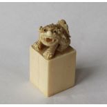 A 19th century Japanese ivory desk seal, with a dog of foo surmount on a rectangular column,
