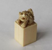 A 19th century Japanese ivory desk seal, with a dog of foo surmount on a rectangular column,