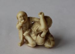 A 19th century Japanese ivory figure group of two men fighting and a boy,