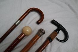 A white metal topped bamboo walking stick together with an antler handled walking stick,